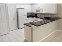 Clean kitchen with white cabinets, black countertops, and white appliances at 1204 L Pavia Blvd # 1204, Venice, FL 34292