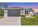 Attached two-car garage with extended driveway, lush lawn, and fresh landscaping at 1207 Henning St, North Port, FL 34288