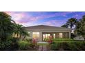 The back exterior of the home featuring a screened-in lanai surrounded by lush landscaping at 12127 Granite Woods Loop, Venice, FL 34292