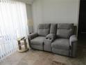 Cozy living room featuring a gray two-seater sofa with recliner, side table and a cream colored lamp at 1255 Tarpon Center Dr # 503, Venice, FL 34285