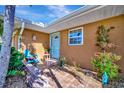 Inviting front entrance features a quaint blue chair, tiled walkway, and flourishing plants at 13534 Alberta Ave, Port Charlotte, FL 33981