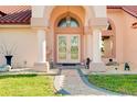 Elegant home entryway with glass double doors, stone columns, and manicured landscaping at 1886 Killdeer Ct, Venice, FL 34293