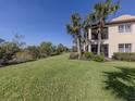 Sprawling green backyard with lush grass and views of trees, bordering a scenic pond and palm trees at 206 Bella Vista Ter # 29A, Nokomis, FL 34275