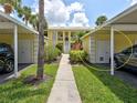 View of property featuring assigned covered parking, a sidewalk, and well-maintained landscaping at 418 Cerromar Ct # 261, Venice, FL 34293