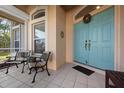 Welcoming front entrance with a charming teal door, decorative wreath, and seating area on the covered porch at 456 Pinewood Lake Dr, Venice, FL 34285