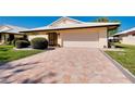Charming one-story home showcasing a brick driveway, lush landscaping, and attached garage at 49 Sandstone Cir, Venice, FL 34293
