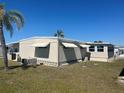 Rear exterior view of home with awning-covered windows and a well-maintained lawn surrounded by palm trees at 508 Vasto Dr, Venice, FL 34285