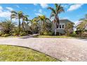 Beautiful home featuring a circular driveway, mature palm trees, and lush green landscaping at 524 Lyons Bay Rd, Nokomis, FL 34275