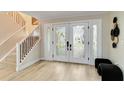 Bright foyer featuring wood floors, staircase with iron railings, and decorative glass double doors at 524 Lyons Bay Rd, Nokomis, FL 34275