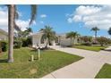 Well-maintained single-story home with lush landscaping, mature palm trees, and a paved driveway at 614 Pond Willow Ln, Venice, FL 34292