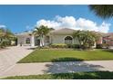 Charming single-story home with a well-manicured lawn, lush landscaping, and a paver driveway at 614 Pond Willow Ln, Venice, FL 34292