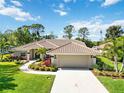 Inviting home with a tile roof, manicured lawn, mature landscaping, and a spacious driveway leading to the garage at 7324 Links Ct, Sarasota, FL 34243
