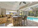Elegant outdoor kitchen features a built-in grill, bar seating, stone accents, and views of the screened pool area at 7324 Links Ct, Sarasota, FL 34243