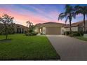 Sunset view of a charming single-story home with a tile roof, two-car garage, and beautiful front lawn at 124 Pesaro Dr, North Venice, FL 34275