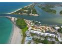 Stunning aerial view showcasing beachfront condos next to blue waters, coastal inlets, and lush island landscape at 1555 Tarpon Center Dr # 255, Venice, FL 34285