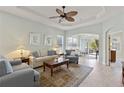 Bright living room with tile floors, tray ceilings, ceiling fan, and sliding glass doors to outdoor patio at 1572 Monarch Dr, Venice, FL 34293