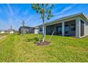 Spacious backyard featuring a grassy lawn, mature trees, and a covered patio area at 1606 Cedar Valley Dr, Port Charlotte, FL 33953
