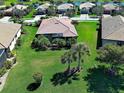 An aerial view of the home displaying a spacious yard, mature landscaping, and neighborhood pond at 19911 Quisto St, Venice, FL 34293