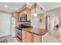 Cozy kitchen featuring wood cabinetry, granite countertop space and modern stainless-steel appliances at 200 The Esplanade N # B3, Venice, FL 34285