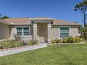 Inviting front entrance with a neutral colored door, manicured flower bed and a walkway at 2098 Zellwood Ter, North Port, FL 34286
