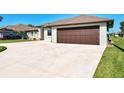 Close up of a two car garage with long driveway and tropical plants at 21 Medalist Ln, Rotonda West, FL 33947