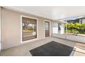 Enclosed lanai featuring neutral tones, a sleek black rug, large picture window and an entry door at 2209 Woodmere Rd, Venice, FL 34293