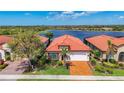 Aerial view showcasing the home's terracotta roof, manicured landscaping, and peaceful lake view at 23823 Waverly Cir, Venice, FL 34293
