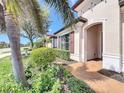 Inviting front entrance features an arched doorway and lush landscaping, including palm trees and flowering plants at 23823 Waverly Cir, Venice, FL 34293