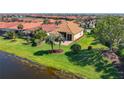 Lovely exterior shot of home with a brown roof, green grass and landscaping with a pond nearby at 23901 Waverly Cir, Venice, FL 34293