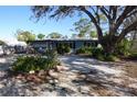 Charming single-story home with a gravel yard and a large tree providing shade at 332 E Langsner St, Englewood, FL 34223