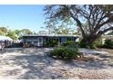 Charming single-story home with a gravel yard and a large tree providing shade at 332 E Langsner St, Englewood, FL 34223