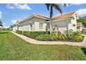 A single-story home with tile roof, manicured hedges, and lush lawn along the sidewalk at 651 Back Nine Dr, Venice, FL 34285