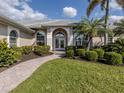 Stately front entrance with manicured lawn and lush tropical landscaping at 692 Egret Walk Ln, Venice, FL 34292