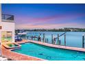 Relaxing backyard oasis featuring a refreshing pool, dock, and boat lift against a picturesque sunset backdrop at 919 Key Way, Nokomis, FL 34275