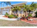 Front entrance to a tan house with landscaping including mulch, rocks, shrubs, and palm trees at 951 Sea Fox Rd, Venice, FL 34293