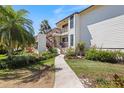 Inviting two-story condo building with well-maintained landscaping, a sidewalk, and a charming wooden staircase at 990 Bird Bay Way # 258, Venice, FL 34285
