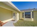 Inviting front entrance featuring a decorative front door, manicured lawn, and a covered porch with ample natural light at 1003 N Gondola Dr, Venice, FL 34293