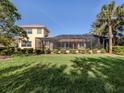 Expansive backyard featuring a screened-in lanai, lush green lawn, and mature palm trees at 101 Portofino Dr, North Venice, FL 34275