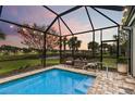 Screened-in pool area with cozy seating and serene sunset views over the lake at 13032 Oriago St, Venice, FL 34293