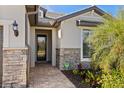 Inviting front entry featuring a brick walkway, stone accents, and lush tropical landscaping at 13251 Borrego St, Venice, FL 34293