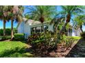 Exterior view of this lovely home featuring lush landscaping, mature palm trees, and a screened-in lanai at 1400 Colony Pl, Venice, FL 34292