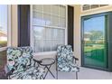 Cozy outdoor seating area featuring two floral chairs and a glass-topped table by the entrance at 1567 Monarch Dr, Venice, FL 34293