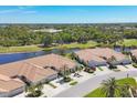 Beautiful aerial view of villa homes overlooking a lake and golf course, complemented by mature trees at 1853 San Silvestro Dr, Venice, FL 34285