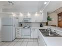 Bright kitchen featuring white appliances, cabinetry, and countertops with stainless steel sink and tile flooring at 206 Silver Lake Dr # 105, Venice, FL 34292