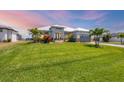 Expansive green lawn complements this single-story home with meticulous landscaping, palms, and gray brick driveway at 226 W Pine Valley Ln, Rotonda West, FL 33947