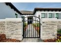 Inviting home entrance featuring a stone wall and secure black iron gate leading to the front door at 265 Bocelli Dr, Nokomis, FL 34275