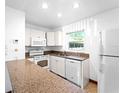 Well-lit kitchen featuring white cabinetry, granite countertops, and modern white appliances at 510 Airport E Ave # 2D, Venice, FL 34285