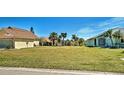 Spacious front yard featuring green grass and tropical landscaping in a desirable neighborhood at 589 Rose Apple Circle, Port Charlotte, FL 33954