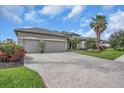Wide brick paver driveway leading to a spacious two-car garage, with lush landscaping at 988 145Th Street Ne Cir, Bradenton, FL 34212