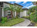 Inviting front entrance with columns, a brick walkway, and lush, manicured landscaping at 988 145Th Street Ne Cir, Bradenton, FL 34212